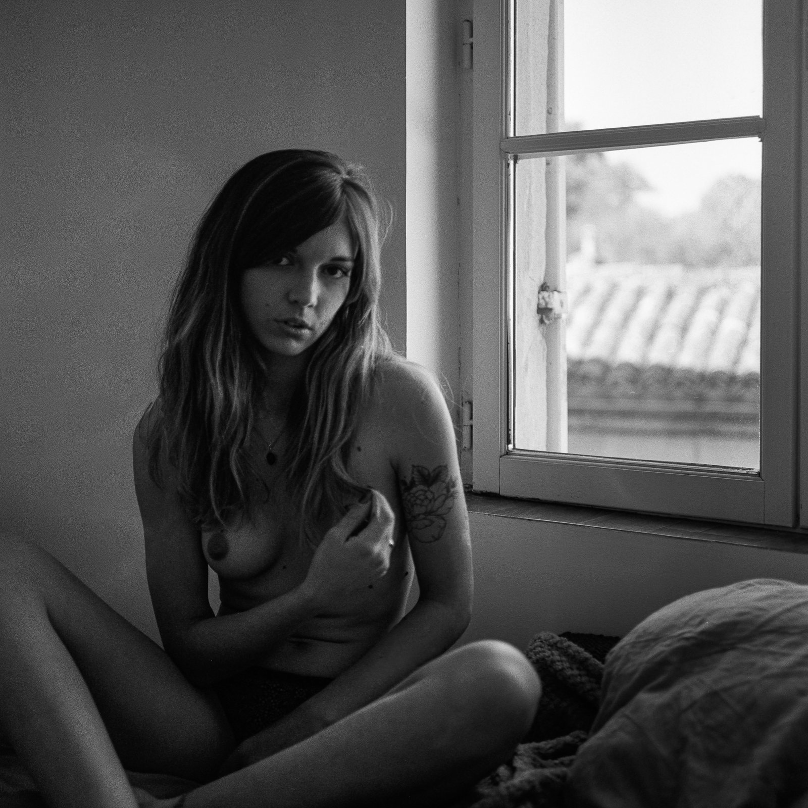 Femme assise près d'une fenêtre ouverte, lumière du matin