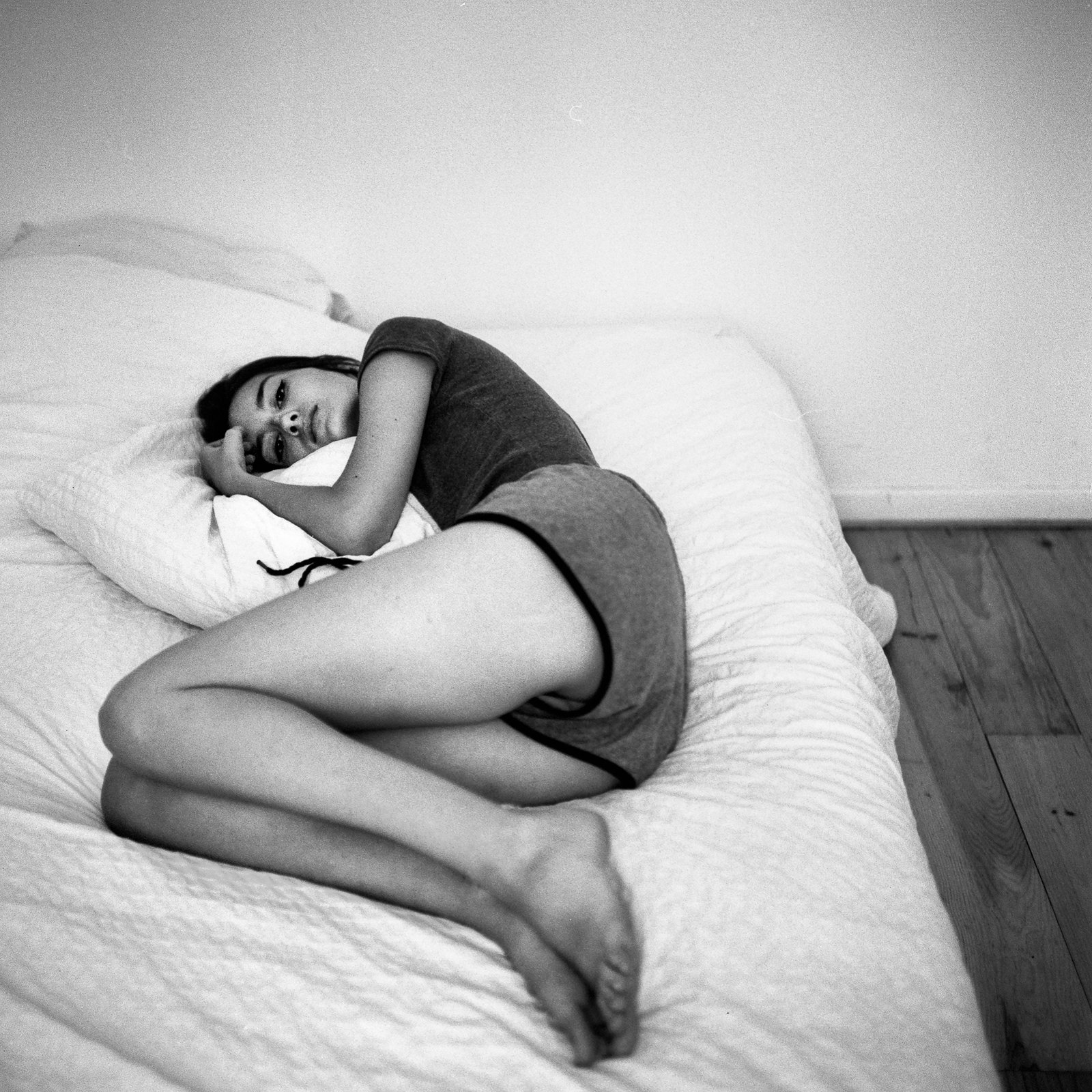 Femme recroquevillée sur un lit