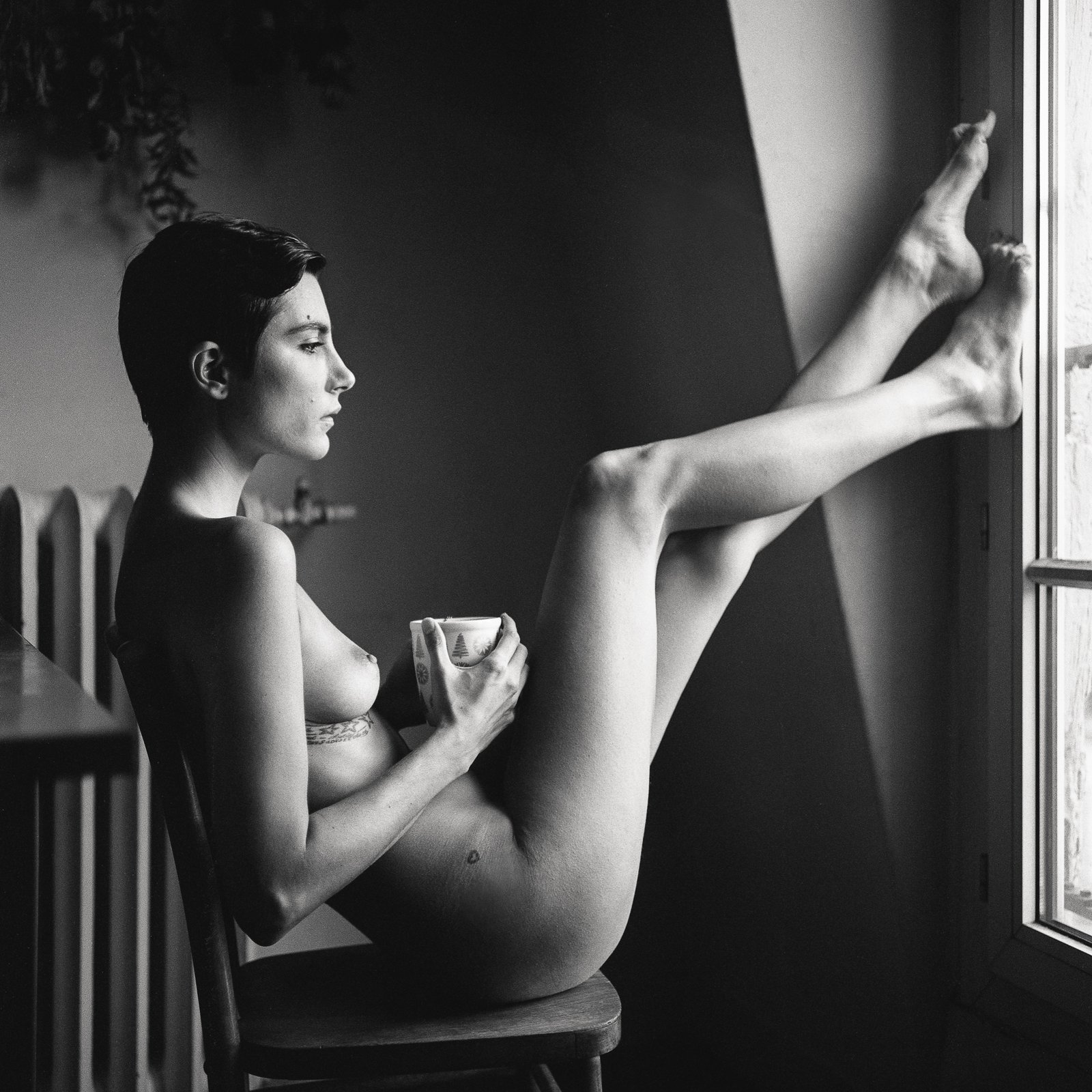 Nu assis, jambes levées, tasse à la main