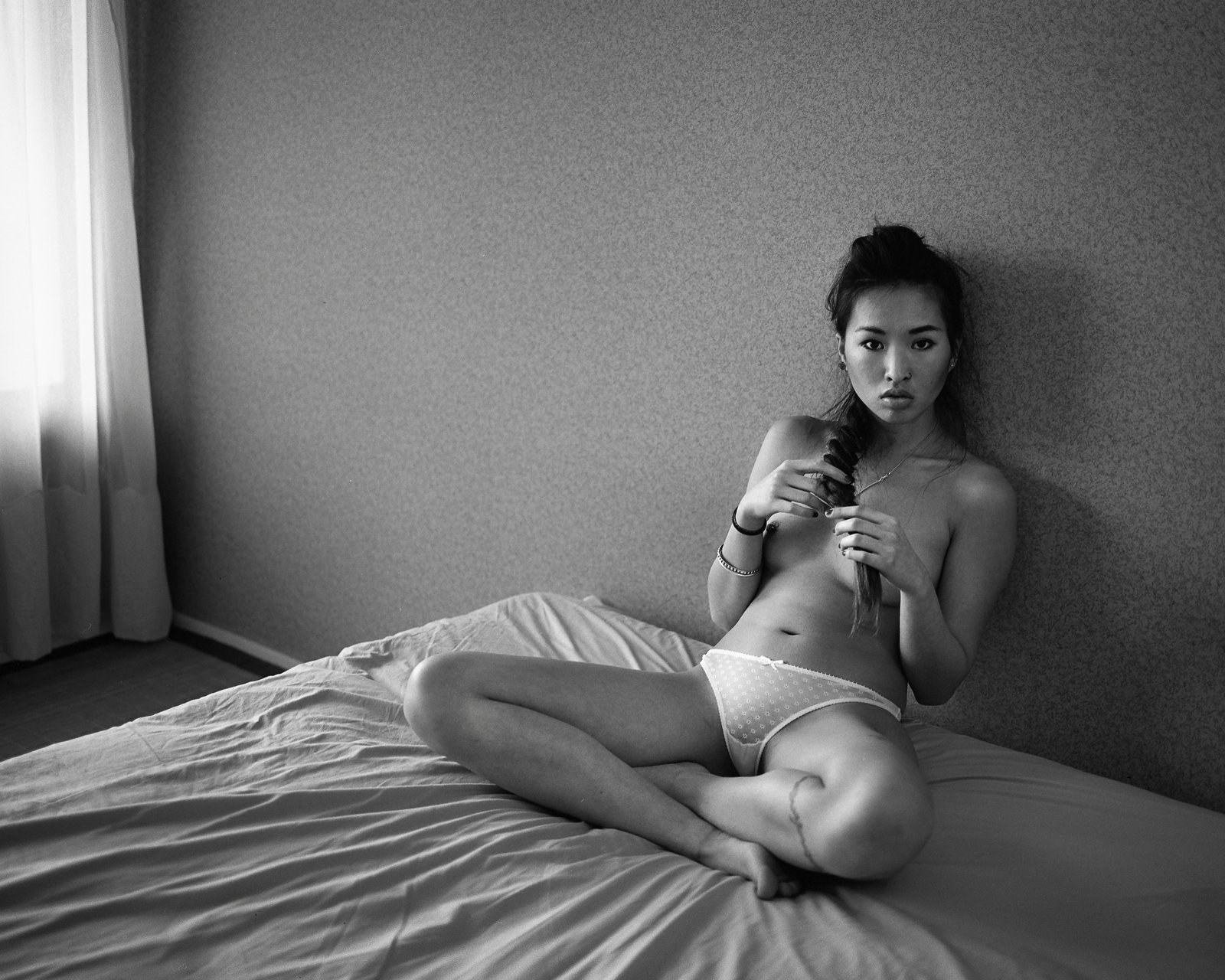 Nu assis sur un lit, téléphone à la main