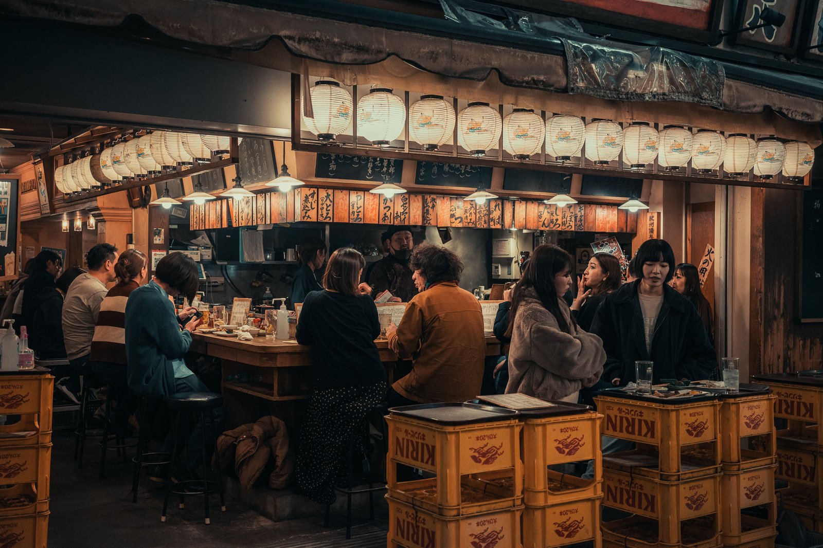 Comptoir d'un izakaya sous les lanternes rouges