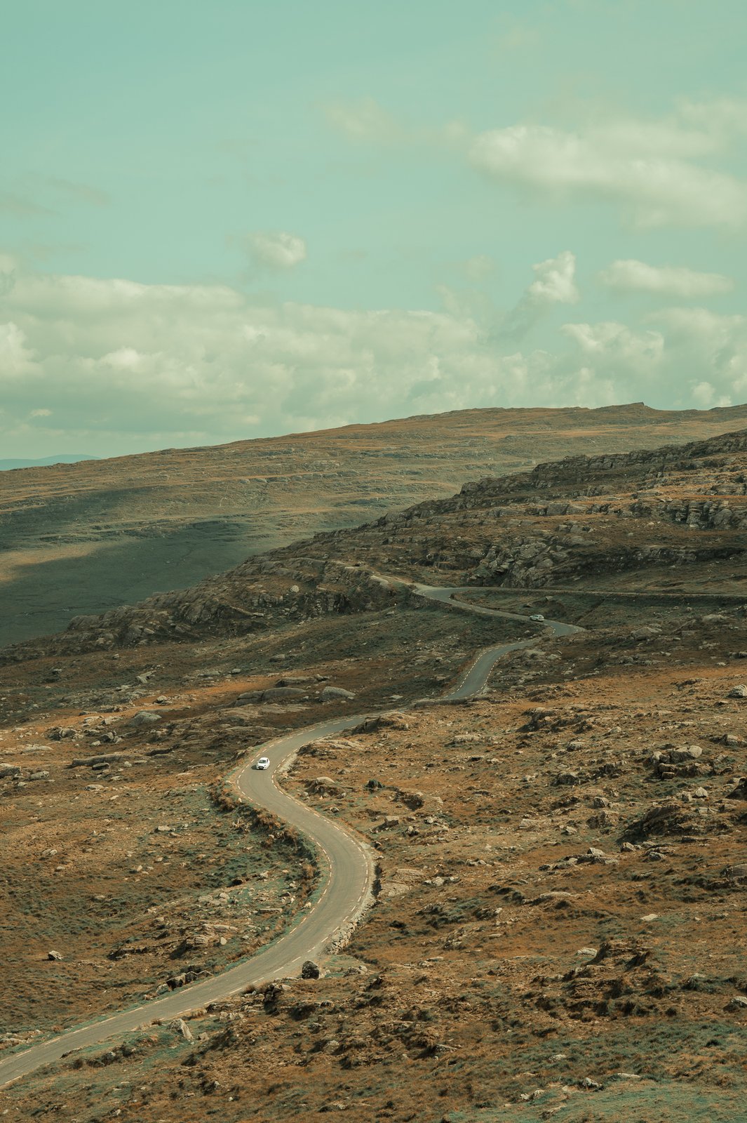 Route sinueuse en lande, une voiture au loin