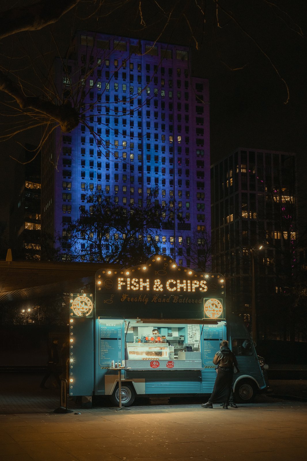 Camion à fish and chips la nuit, tours illuminées en arrière-plan