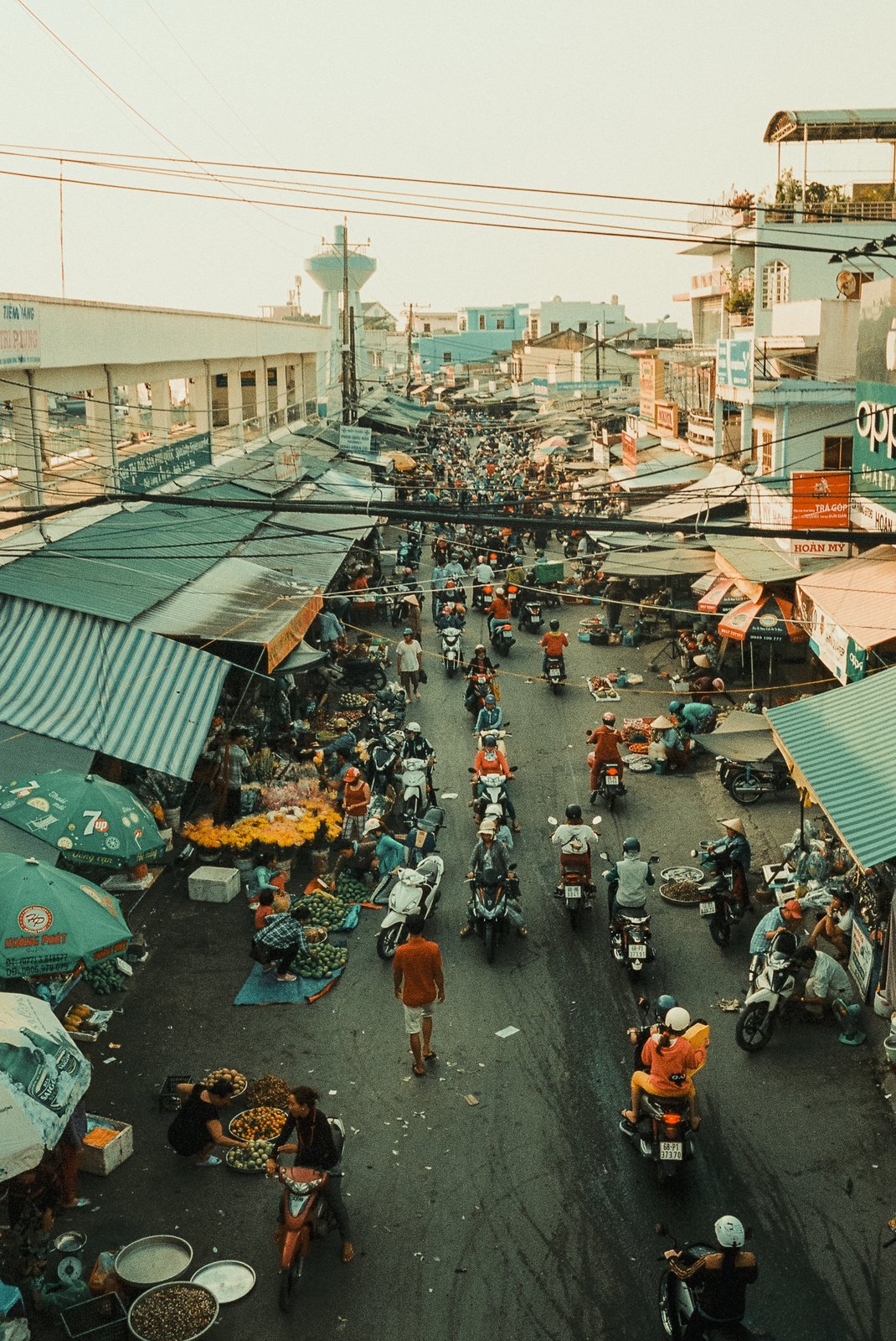 Marché de rue animé vu d'en haut, scooters et étals