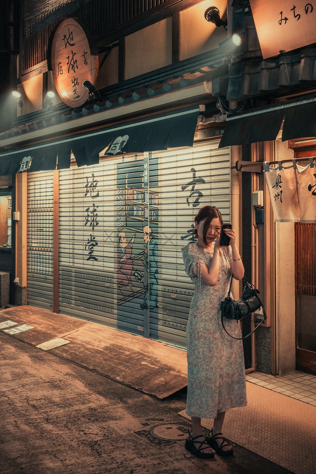 Femme photographiant une devanture fermée, ruelle japonaise
