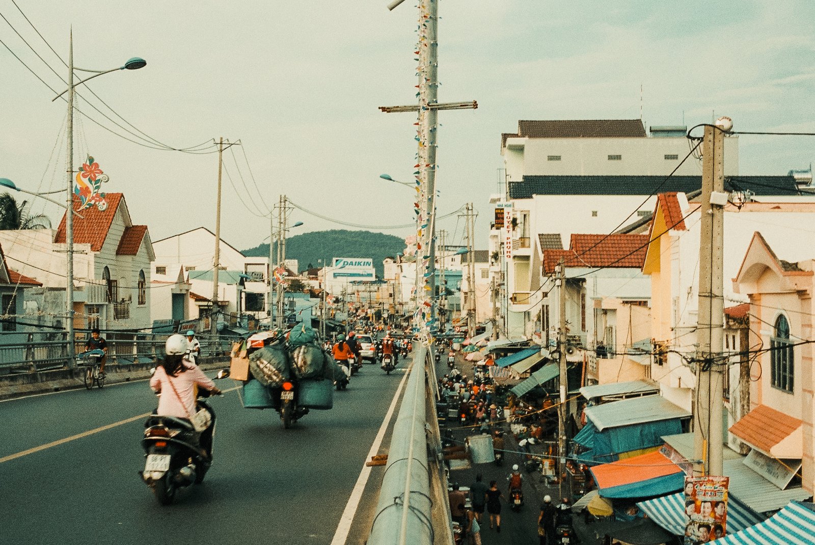 Rue animée vue depuis un pont, scooters et marché
