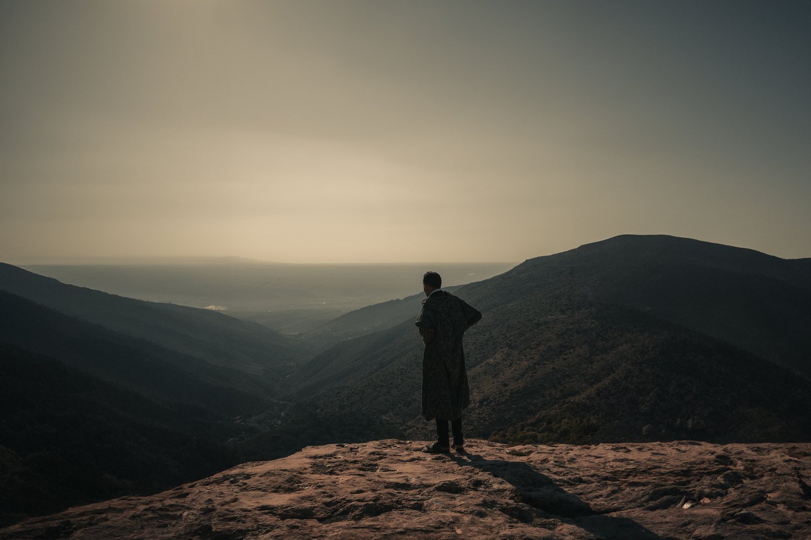 Silhouette en djellaba face à la vallée au coucher du soleil, Maroc