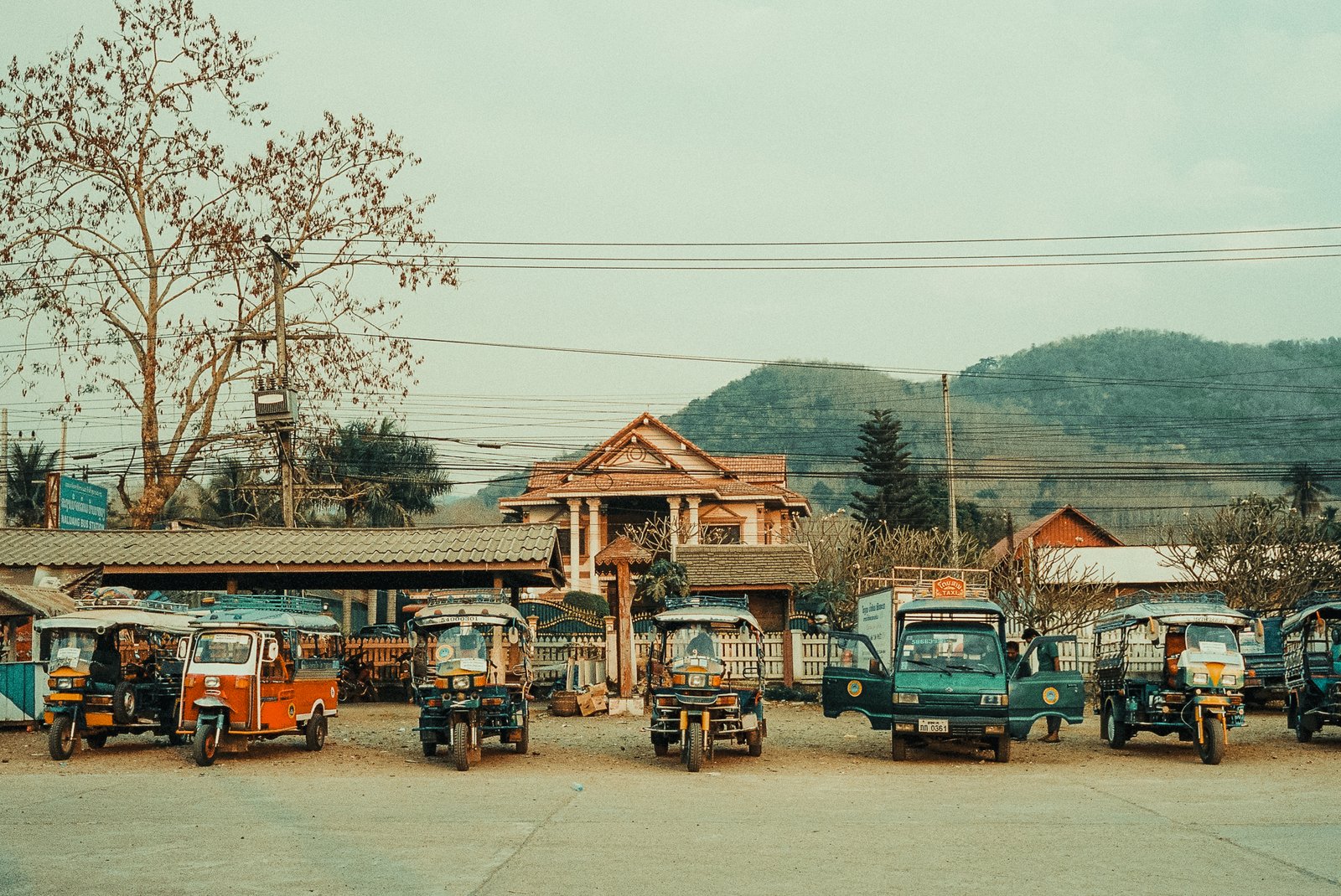 Tuk-tuks garés devant une maison traditionnelle, Laos