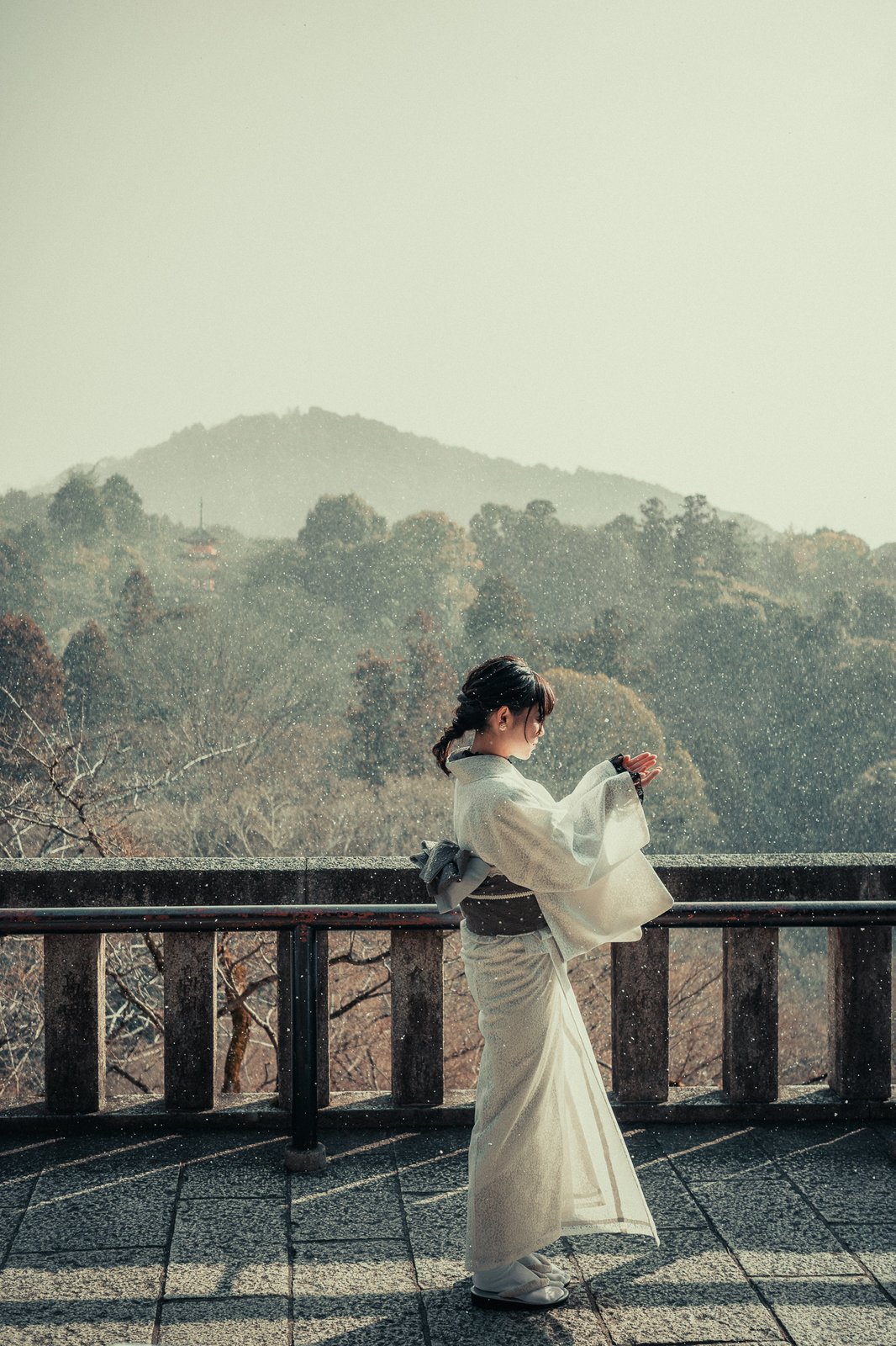 Femme en kimono blanc sur une terrasse, neige légère, Kyoto