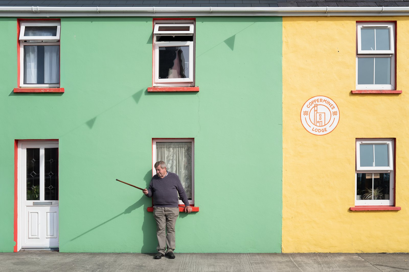 Maison colorée vert et jaune, homme appuyé au mur, Irlande